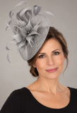 Silver-grey sinamay fascinator with feathers on a mature brunette model
