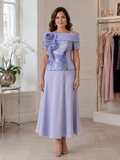 Lilac mother of the bride outfit with floral bodice, off-the-shoulder collar and flowing organza skirt.