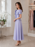 Side view of a soft lilac occasion outfit with sculpted flower detail and tea-length A-line skirt.