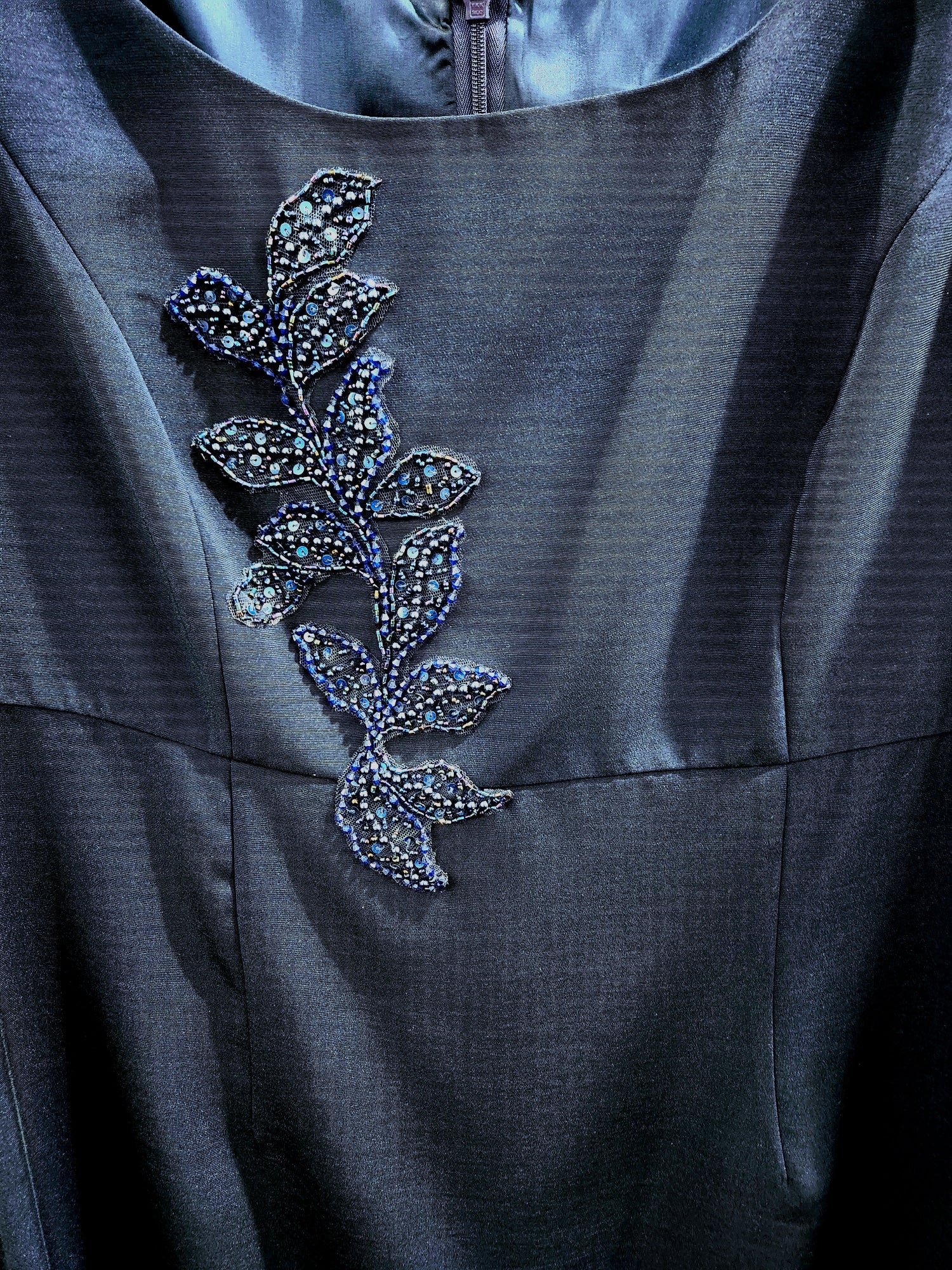 Dark gray fabric with a decorative leaf pattern featuring small stones or beads.