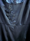 Dark gray fabric with a decorative leaf pattern featuring small stones or beads.