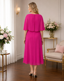 Back view of hot pink chiffon wedding guest dress by Lizabella featuring elegant cape overlay and flowing skirt
