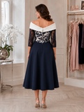 Back view of navy and ivory occasion dress with off-the-shoulder neckline, lace sleeves and full crepe skirt.