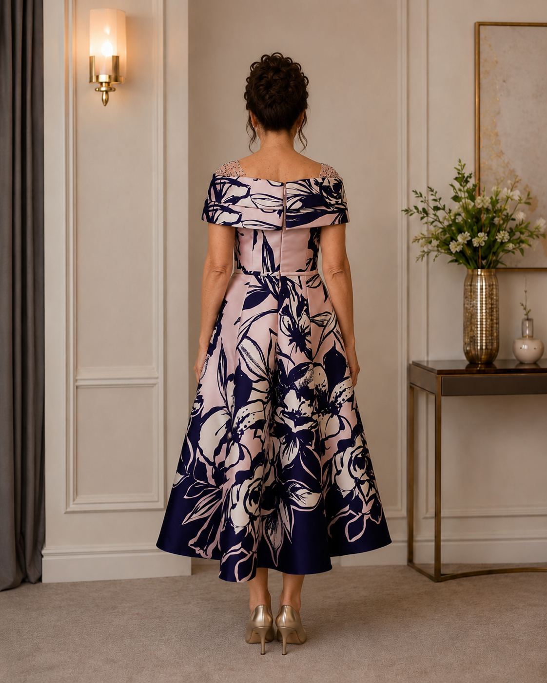 Back view of blush pink and navy occasion dress with folded neckline, fitted waist and floral midi skirt.