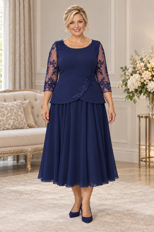 Navy plus size dress with lace sleeves, crepe peplum bodice and full chiffon midi skirt, shown from the front on a blonde model.