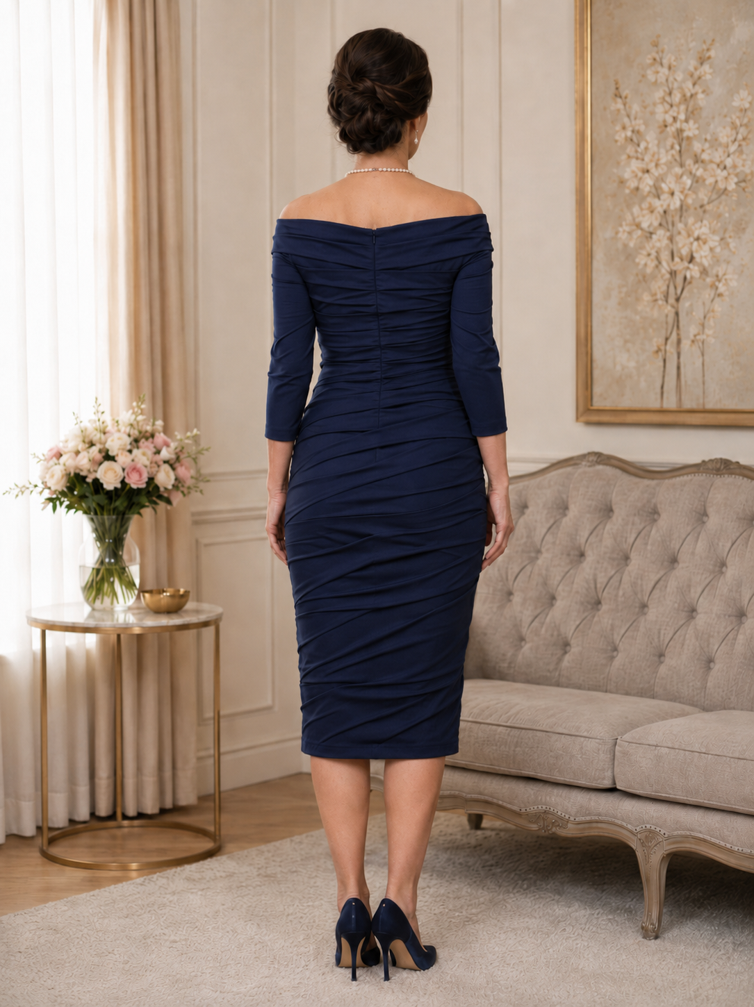 Back view of dark navy fitted occasion dress with folded fabric detail, Bardot neckline and below-knee hem
