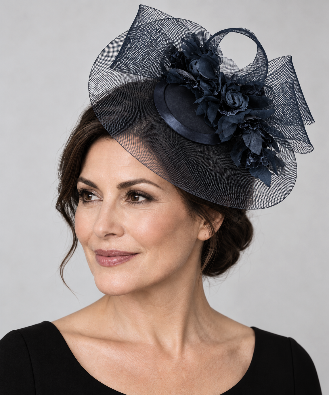 Dark navy Cupids fascinator worn beside the crown by a mature model