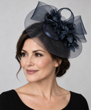 Dark navy Cupids fascinator worn beside the crown by a mature model