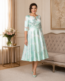 Mint and ivory floral jacquard mother of the bride dress with three-quarter sleeves and circular tea-length skirt.
