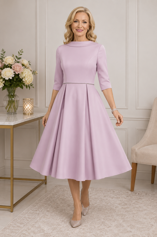 mother of the bride wearing a dusty rose tea-length occasion dress with sleeves and diamante waist detail in an elegant indoor setting