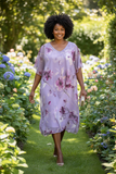Mature model wearing lilac floral knee-length dress with floaty chiffon overlay and silver accessories