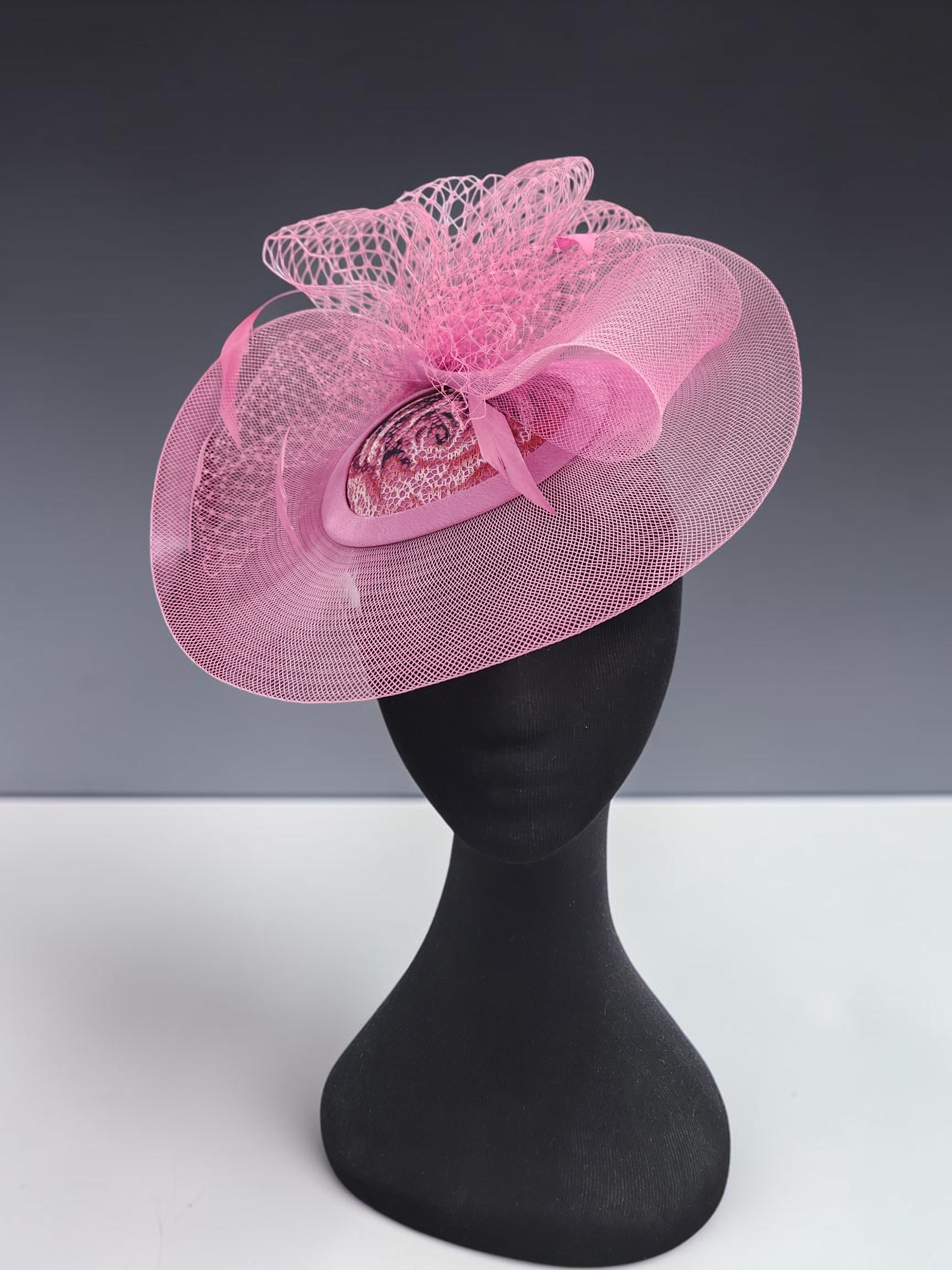 Close-up of pink occasion fascinator with patterned fabric centre and mesh loops