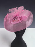 Close-up of pink fabric occasion fascinator with patterned centre and mesh loops 