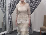 Video of a champagne beaded fringe mother of the bride dress showcasing the front, side and back views, highlighting intricate beadwork, tiered fringe detailing and elegant movement on a brunette size 12–14 model.