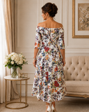 Back view of ivory multicoloured floral dress with folded Bardot neckline, central zip and longer back hem.