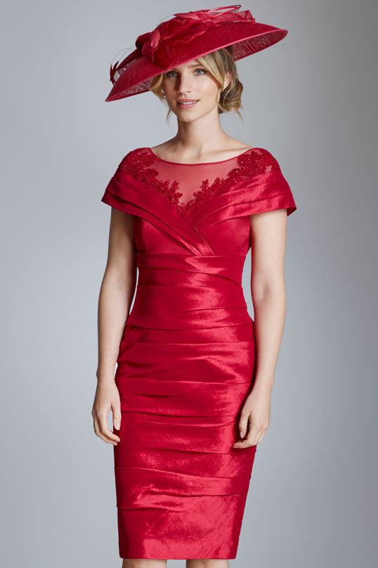 Red ruched dress with floral details and matching hat on a smiling woman